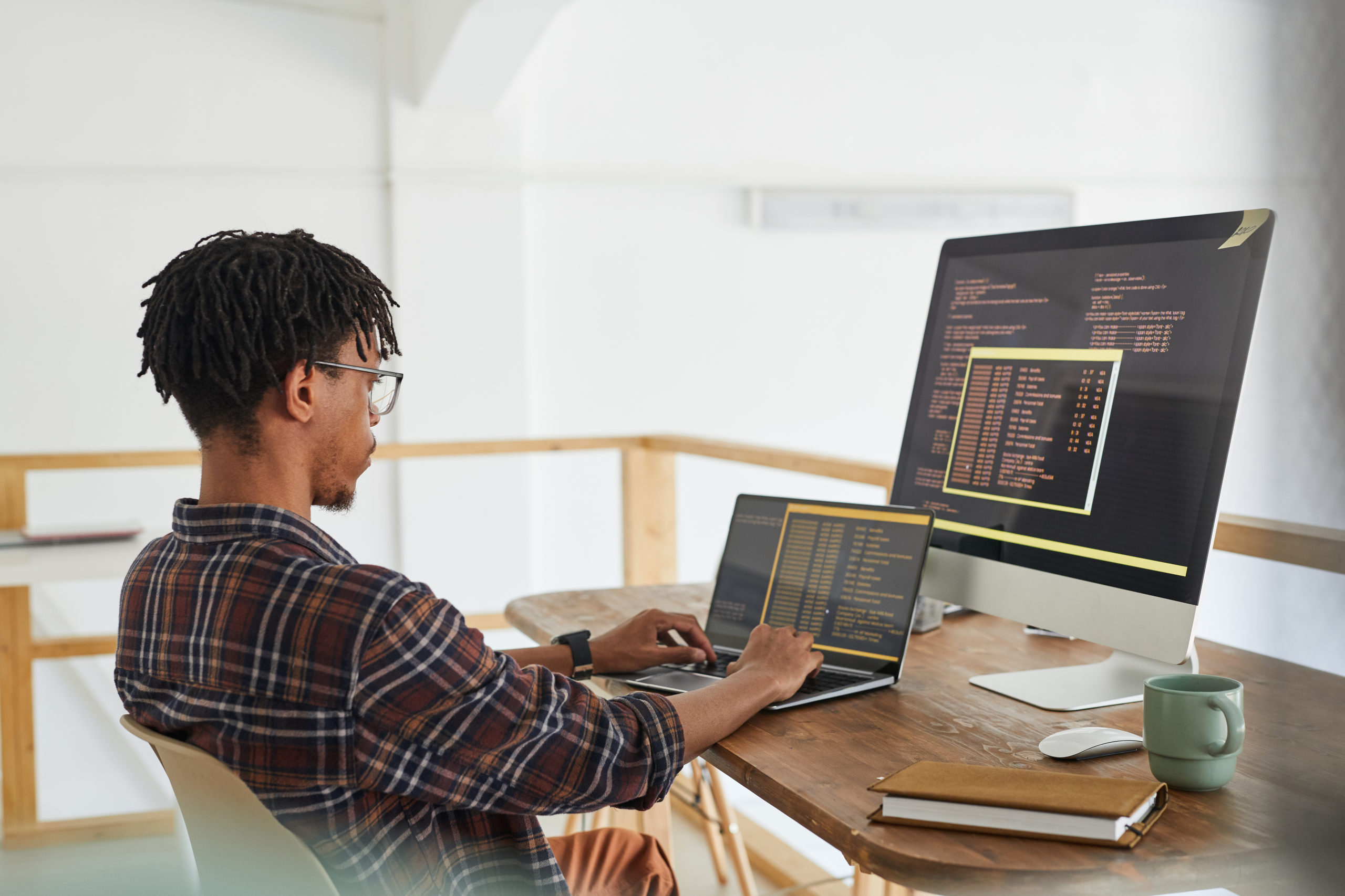 Man programming on multiple screens in a modern workspace.
